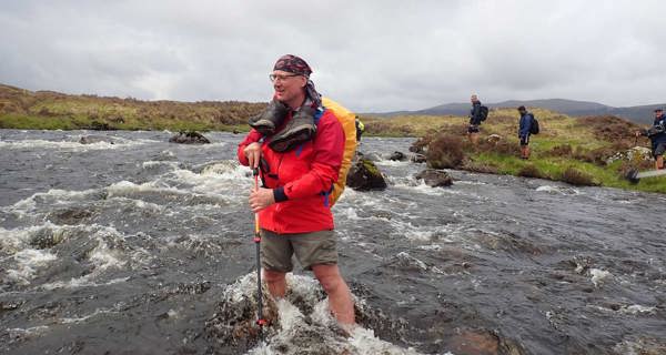 Colleagues crossing river during Rannoch Moor trek