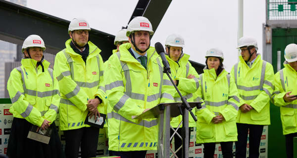 Ed McAlpine talking at a lectern with guests assembled behind him
