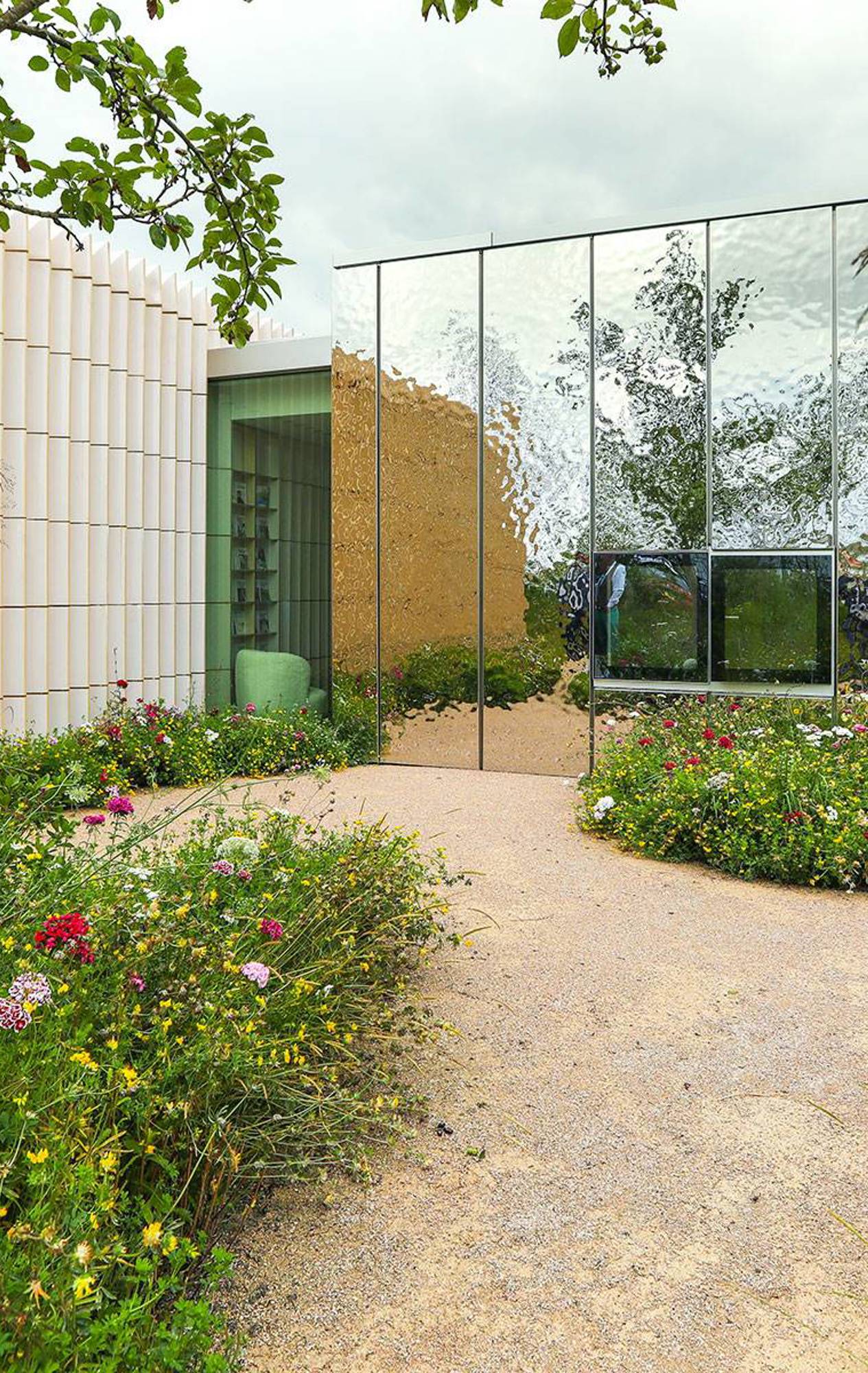 Exterior view of Maggie’s Southampton surrounded by a verdant garden with perennials and various tree species.