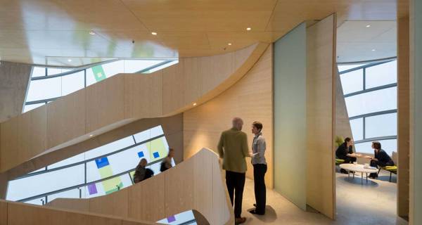Interior view of the gently rising bamboo staircase at Maggie’s Barts, which curves around the central space, mirroring the curving lines of the external facade.