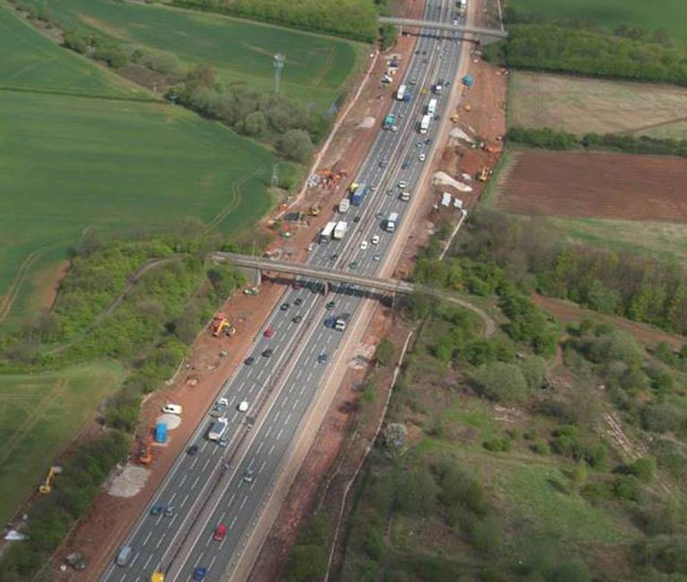 Aerial view of the M1 motorway during the widening project, showing construction machinery and the newly added lanes to improve traffic flow.